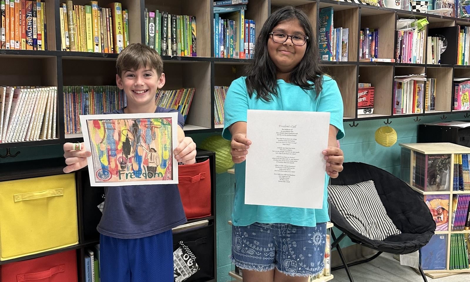 Two students hold up art pieces